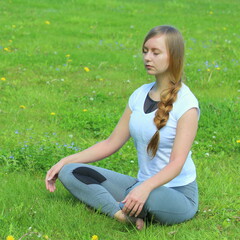 Young woman of European appearance does yoga in summer nature
