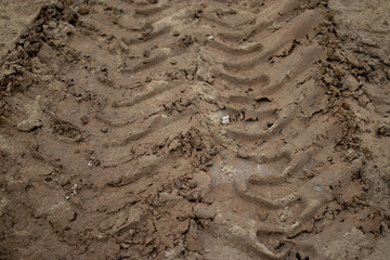 Deep trace tractor wheel in brown sand, dirt road