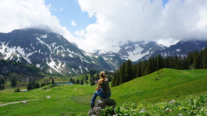 a woman sitting on a rock at the Körbersee in the state Vorarlberg in the month of June, Austria