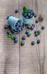 Blueberries in two blue tin cans overhead vibrant color arrangement on brown wooden kitchen table studio shot