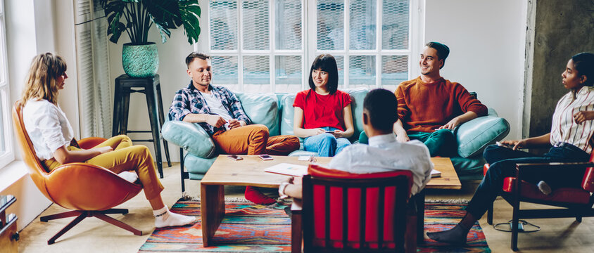 Happy Adult Diverse Friends Having Nice Conversation During Discussion Of Startup Project At Home