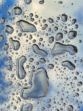 Rain Droplets On Glass Surface With Reflection Of Sky. No People