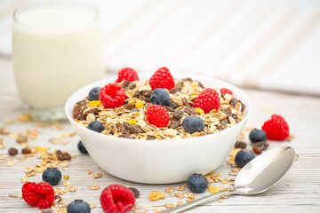 Breakfast Served in the morning with corn flakes Whole grains and raisins with milk in cups and Strawberry, Blueberry, Raspberry, Kiwi on the wood table,Diet food or healthy food in the morning.