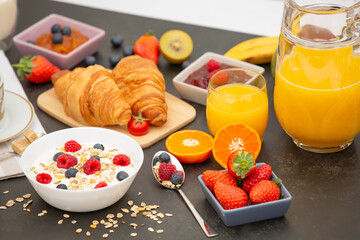Breakfast Served in the morning with Coffee, Butter croissant and corn flakes Whole grains and raisins with milk in cups and Strawberry, Raspberry, Kiwi, Fresh Orange Juice on the breakfast table.