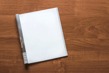 Mockup of magazine on wooden brown table. Empty isolated white page. Top view