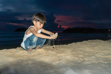 A boy playing sand in twilight on Kata beach Phuket Thailand.. © Narong Niemhom
