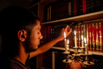 Boy holding book from the library in the dark with candles to light his way