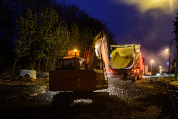 Fototapeta na wymiar Orange excavator digger working at night on the street