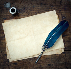 Old quill pen, and old paper blank sheet and vintage inkwell on wooden desk in the old office . Retro style. Conceptual background on history, education, literature topics. - obrazy, fototapety, plakaty
