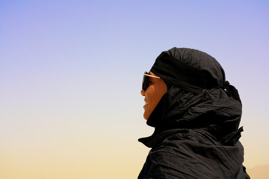 Beautiful young woman model portrait with sunglasses in black abaya with creal blue sky