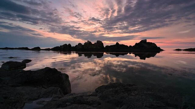 Video with rotation of a colorful sunrise sky at rocky coastline and calm summer sea, the Black Sea coast, Bulgaria