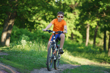 A child in sun glasses rides a bicycle through the woods