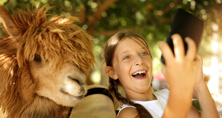 Selfie time in the zoo! People and holiday concept. Cute girl with her  friend lama making selfie,...