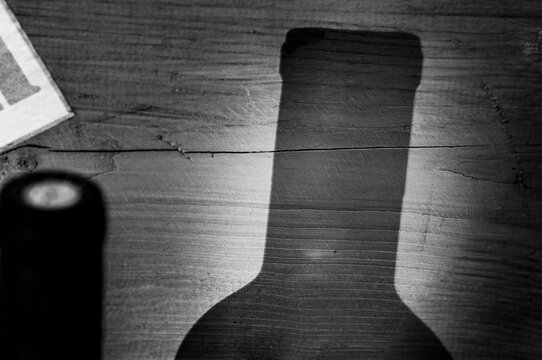 shadow of an isolated bottle of wine on a wooden background. black and white picture
