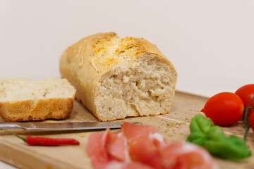 Homemade white bread on wooden board with cold meat and vegetables