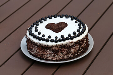 Fresh and delicious homemade summertime theme black currant, chocolate and cream cake. Topped with whipped cream, fresh berries and grated chocolate. Closeup color image.