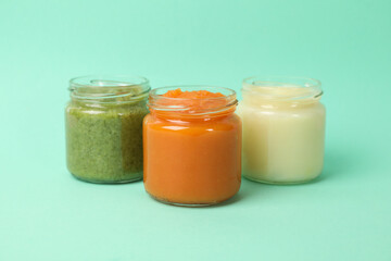 Glass jars with vegetable puree on mint background. Baby food