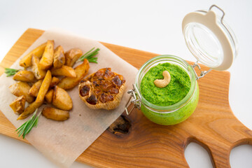 Baked potatoes with rosemary, garlic and pesto on a wooden board