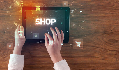 Close-up of a hand holding tablet with SHOP inscription, online shopping concept