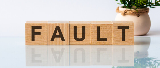 FAULT word made on wooden cube blocks and flower in a pot on background. Fault and medicine concept. Image concept.