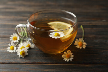 Cup of chamomile tea on wooden background, close up
