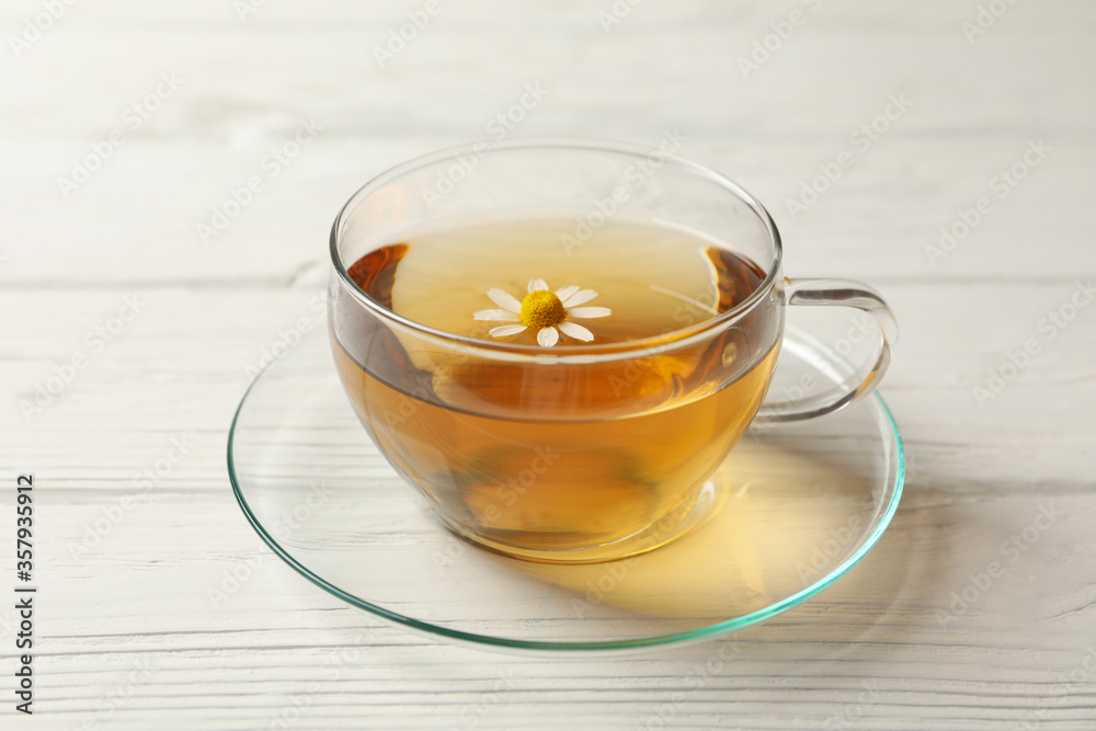 Wall mural glass cup of chamomile tea on wooden background, close up