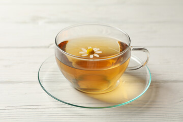 Glass cup of chamomile tea on wooden background, close up