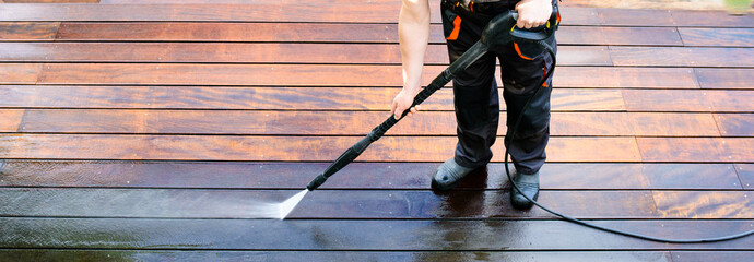 power washing - man cleaning terrace with a power washer - high water pressure cleaner on wooden...