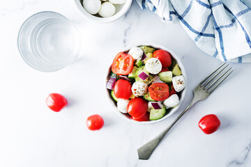 Mozzarella cucumber tomato red onion salad in a white bowl