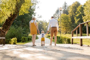 Family mom, small child, dad holding hands walking in the Park.Bright yellow stylish outfits family look