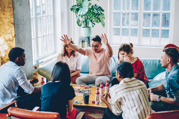 Amazed hipster guy get victory in poker spending leisure time with multicultural young people