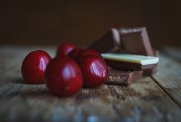 pieces of chocolate lying on the old village table next to the cherries