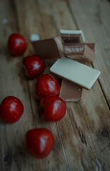 pieces of chocolate lying on the old village table next to the cherries