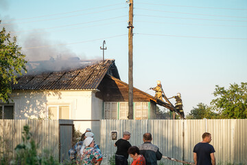 Firefighters in the form of the Ministry of Emergency Situations on the roof extinguish a burning...