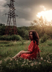 A girl in a red dress is sitting on the grass