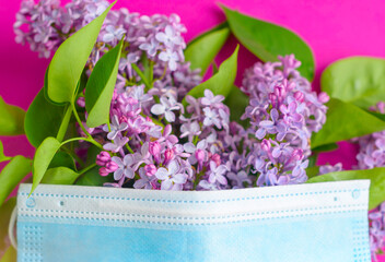 protective face mask and lilac on a purple background