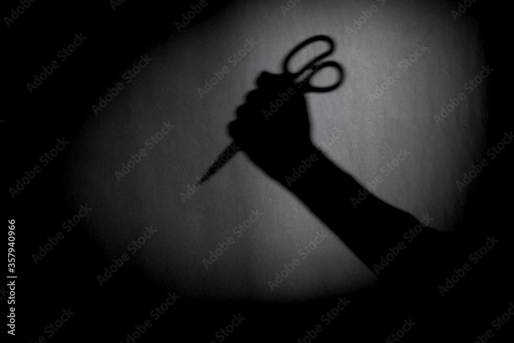 Wall mural man with scissors silhouette over dark wall. black and white photo can be used for illustrating horr