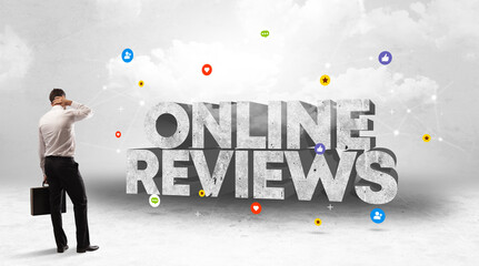 Young businessman standing in front of ONLINE REVIEWS inscription, social media concept