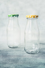 Two empty glass bottles with lid on grey background. Copy space