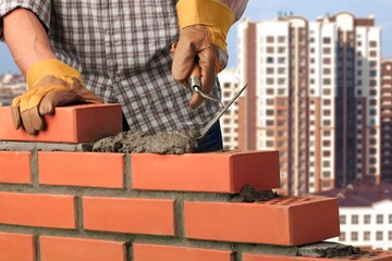 Man worker installing brick masonry wall with a trowel