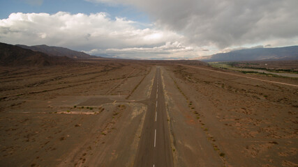 Travel. Asphalt highway across the arid desert. Wide empty road into the mountains.
