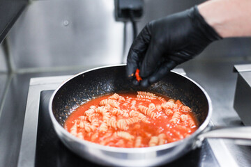 A process of cooking tomato pasta in a restaurant kitchen. Fresh made pasta on a pan