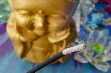 Smoking incense stick with buddha statue in the background