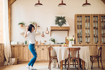A young woman performs a joyful victory dance in the middle of the kitchen at home