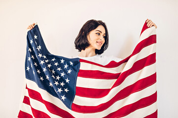 Lifestyle portrait of a happy young woman holding an American flag on US Independence Day, July 4th