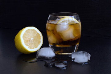 alcohol refreshing cocktail with lemon and ice on a dark background