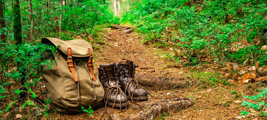 Hiking nature background - Close up from rustic leather hiking boots and hiking backpack on ground...