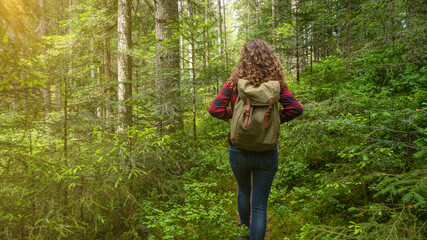 Hiking nature outdoor background - Young pretty girl woman with curly hair and backpack on her back...