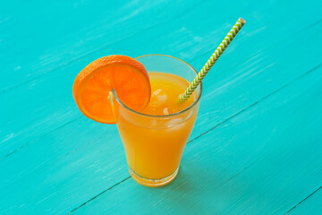 Orange juice in a glass on turquoise blue wooden table, top view