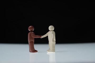 Black man and white man figurines shake hands - 357944700